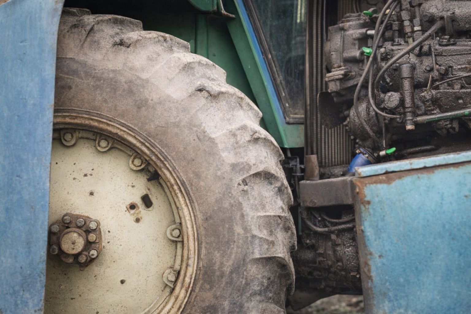 Närbild på hjulet och motorn på en äldre traktor vid en lantbruksauktion.